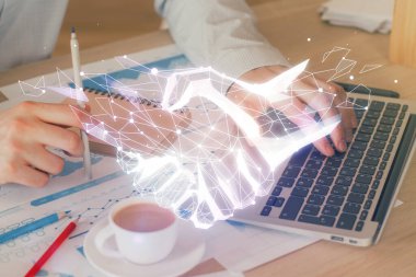 Bilgisayarda çalışan bir iş adamıyla el sıkışma hologramı çizimi. Çift pozlama.