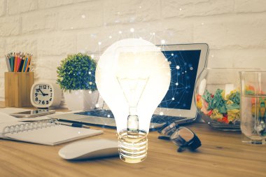 Bilgisayar ofisinde ampul simgesi hologramıyla birlikte. Çifte maruziyet. Fikir kavramı.