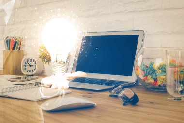 Bilgisayar ofisinde ampul simgesi hologramıyla birlikte. Çifte maruziyet. Fikir kavramı.