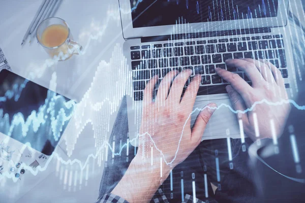 Doble exposición de las manos del hombre escribiendo sobre el teclado portátil y el dibujo del holograma gráfico de divisas. Vista superior. Concepto de mercados financieros. —  Fotos de Stock