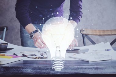 Ampul lambası fikir simgesinin gelecek arayüzü ve yazma adamı el altyapısı üzerindeki görüntüsü. Çift pozlama.