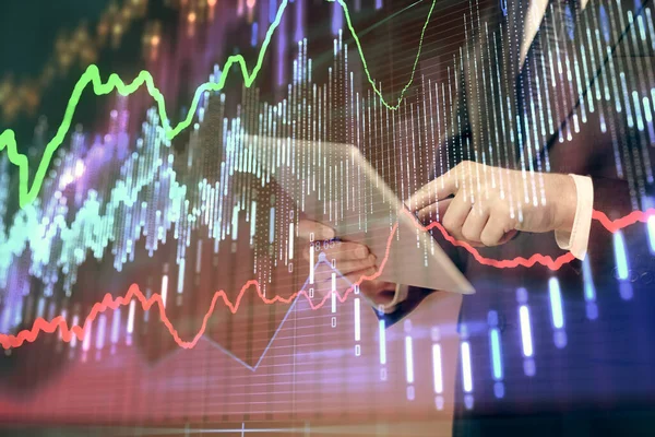 Double exposure of mans hands holding and using a digital device and forex graph drawing. Financial market concept.