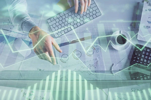 Multi exposure of mans hands typing over computer keyboard and forex graph hologram drawing. Top view. Financial markets concept.