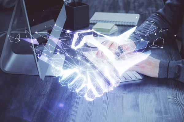 Handshake holograma dibujo con hombre de negocios que trabaja en la computadora en el fondo. Doble exposición. —  Fotos de Stock