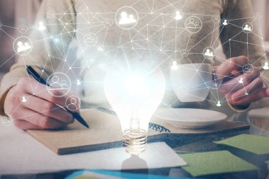 El üstünde tutulan ampul hologramı notlar alıyor. Fikir kavramı. Çift pozlama