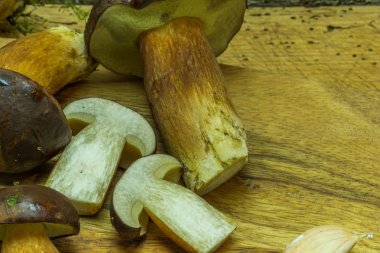 Sebzeler ve taze mantarlar bir bıçakla kesme tahtasının üzerinde yatıyor.