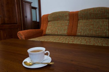 bir daire ve bir kaşık ile beyaz bir kupa kanepe yakınındaki ahşap bir masa üzerinde duran