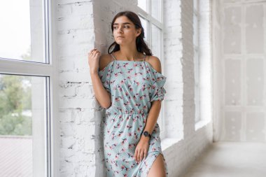 Genç Sevimli seksi sevimli kız Pencerenin kenarında ayakta ahlaksız saçlı pembe elbiseli yaşlı bir masada streç olacak gebe