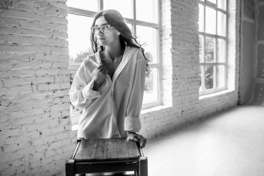 Genç Seksi güzel kız beyaz erkek gömlek çorap ve parlak oda penceresinde yakın bir sandalyede oturan gözlük gebe