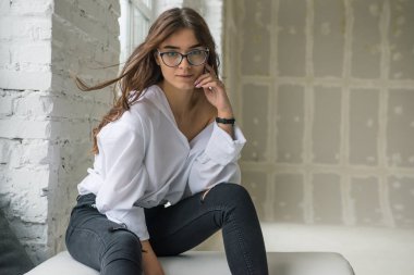 Burada gözlük yalan çevresinde yalan bir uzun saçlı Genç çok seksi çekici kız beyaz adamın gömlek parlak bir oda penceresinde yakınındaki beyaz kanepe oturur 