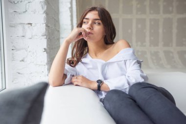 Genç Sevimli seksi sevimli Gözlüklü kız çıplak sarıl bağsız kıl ile büyük bir pencere yakınında ile beyaz bir erkek ceket beyaz kanepe oturur gebe