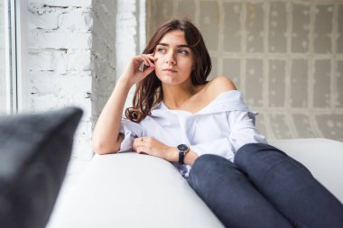 Genç Sevimli seksi sevimli Gözlüklü kız çıplak sarıl bağsız kıl ile büyük bir pencere yakınında ile beyaz bir erkek ceket beyaz kanepe oturur gebe