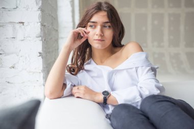 Genç Sevimli seksi sevimli Gözlüklü kız çıplak sarıl bağsız kıl ile büyük bir pencere yakınında ile beyaz bir erkek ceket beyaz kanepe oturur gebe