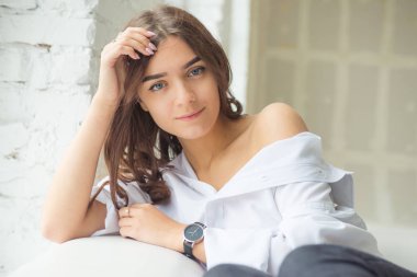 Genç Sevimli seksi sevimli Gözlüklü kız çıplak sarıl bağsız kıl ile büyük bir pencere yakınında ile beyaz bir erkek ceket beyaz kanepe oturur gebe