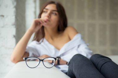 Burada gözlük yalan çevresinde yalan bir uzun saçlı Genç çok seksi çekici kız beyaz adamın gömlek parlak bir oda penceresinde yakınındaki beyaz kanepe oturur 