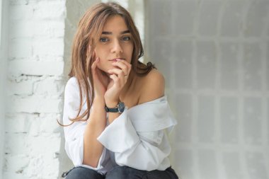 Genç Sevimli seksi sevimli Gözlüklü kız çıplak sarıl bağsız kıl ile büyük bir pencere yakınında ile beyaz bir erkek ceket beyaz kanepe oturur gebe