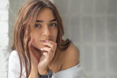 Genç Sevimli seksi sevimli Gözlüklü kız çıplak sarıl bağsız kıl ile büyük bir pencere yakınında ile beyaz bir erkek ceket beyaz kanepe oturur gebe