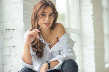 Genç seksi çekici tasarlanmış kız gözlük eliyle giderir ve uzak görünüyor 