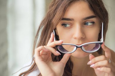 Genç seksi çekici tasarlanmış kız gözlük eliyle giderir ve uzak görünüyor 