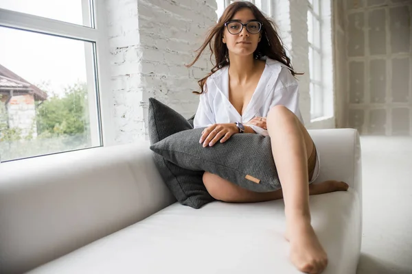 Burada gözlük yalan çevresinde yalan bir uzun saçlı Genç çok seksi çekici kız beyaz adamın gömlek parlak bir oda penceresinde yakınındaki beyaz kanepe oturur 