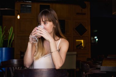 Genç güzel bir kafede oturan ve latte içmek şirin kız