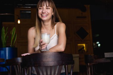 Genç güzel bir kafede oturan ve latte içmek şirin kız