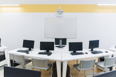 Klavyeli bilgisayar tablolu bir ofis odası ve projektörlü bir fare. 