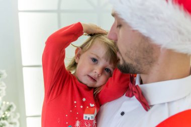 Kırmızı elbise genç adam bir kelebek ve küçük bir kız, yeni yıl'ın giyim, Aile Yılbaşı elbiseli Genç bir aile ile bir sakal ve kırmızı şapkalı güzel ve çekici kız 