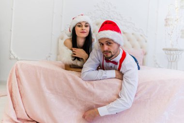 çok güzel bir kız ve çocuk büyük bir yatak üzerinde oturan kırmızı Noel şapka içinde küçük sakallı