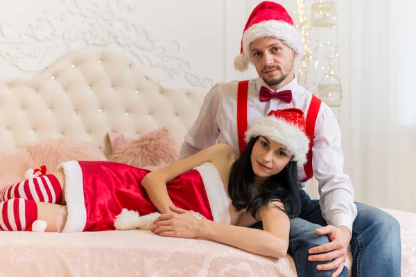 かなり可愛い女の子と大きなベッドの上に座って赤いクリスマス帽子の小さいひげと少年 — ストック写真