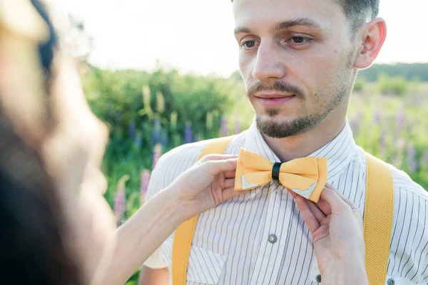 young pretty man with a small beard in a white shirt with yellow pulls holding a butterfly near my lips