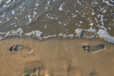 sabah güneşin ışınları ile ıslak kum üzerinde ayak izleri