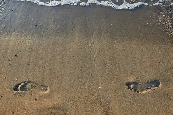 在潮湿的沙滩上留下的脚印 带着清晨阳光的光芒 — 图库照片