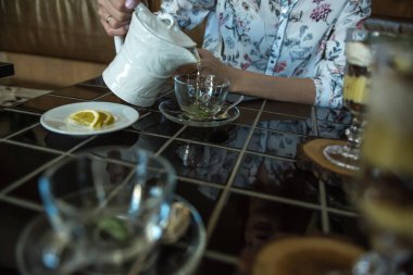 Kız masanın üzerine saydam bir çukurda yeşil çay içiyor ve bir plaka üzerinde bir limon yoktur