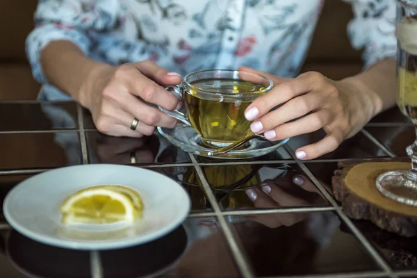Kız masanın üzerine saydam bir çukurda yeşil çay içiyor ve bir plaka üzerinde bir limon yoktur