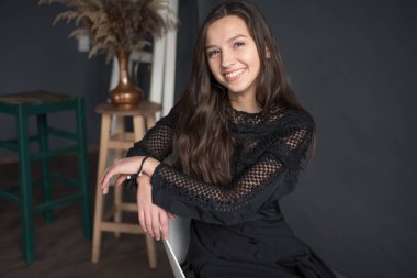 gri bir tuval yakın bir sandalyede oturur ve hafifçe gülümsüyor genç çok tatlı ve çekici kız. Oda rahat gri duvarlar ile