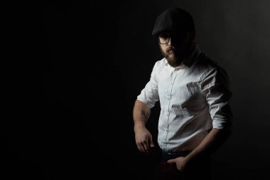 kavga ve bıyık bir siyah şapka ve beyaz bir gömlek, bir karanlık studio arka plan bardaklarda yakışıklı delikanlı