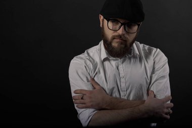Gözlük sakallı genç bir adam ve bıyıklı bir siyah şapka ve beyaz bir gömlek, bir karanlık studio arka plan portresi