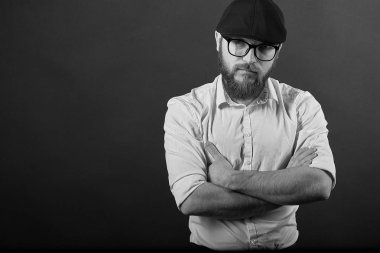 Gözlük sakallı genç bir adam ve bıyıklı bir siyah şapka ve beyaz bir gömlek, bir karanlık studio arka plan portresi