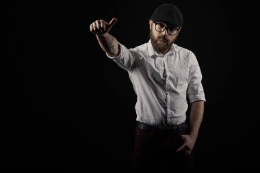 genç yakışıklı adam gözlüklü sakallı ve bıyıklı bir siyah şapka ve beyaz bir gömlek el hareketleri, bir karanlık studio arka plan çeşitli gösterir
