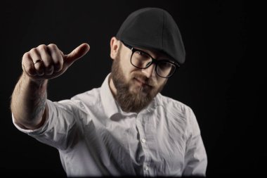 genç yakışıklı adam gözlüklü sakallı ve bıyıklı bir siyah şapka ve beyaz bir gömlek el hareketleri, bir karanlık studio arka plan çeşitli gösterir