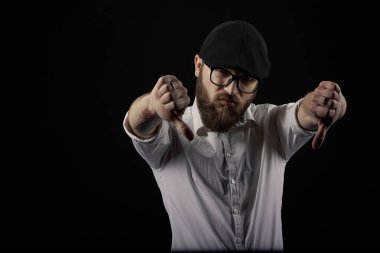 genç yakışıklı adam gözlüklü sakallı ve bıyıklı bir siyah şapka ve beyaz bir gömlek el hareketleri, bir karanlık studio arka plan çeşitli gösterir