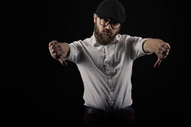 genç yakışıklı adam gözlüklü sakallı ve bıyıklı bir siyah şapka ve beyaz bir gömlek el hareketleri, bir karanlık studio arka plan çeşitli gösterir
