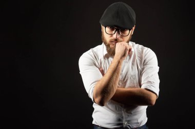 Gözlük sakallı genç bir adam ve bıyıklı bir siyah şapka ve beyaz bir gömlek, bir karanlık studio arka plan portresi