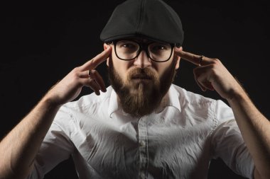 bir sakal ve bir siyah kap ve beyaz bir gömlek bir bıyık ile Gözlük Genç yakışıklı bir adam baş ağrısı gibi kafasına ellerini tutan, karanlık bir stüdyoda