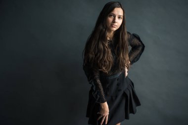 Sevimli sarışın saçlı Genç bir güzel kızın bir portre hoş bir gri arka planda karanlık bir elbise gülümsüyor