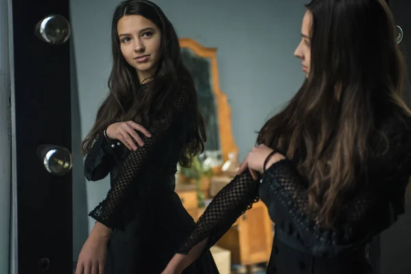 黒板の若いかなり甘くて魅力的な女の子が大きな鏡の近くに立って 彼女の反射が見える 居心地の良いグレーの壁のある客室 — ストック写真
