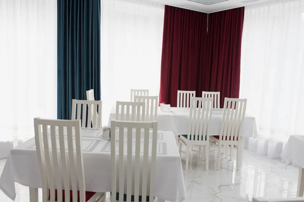 light reception dining room with red and blue walls, with a large light table and armchairs