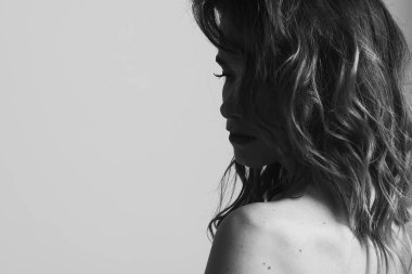 genç, sempatik, seksi, Avrupalı, yan lara ve düşünceli bir şekilde görünen tüysüz saçlı bir kızın portresi. Açık arka planda, siyah beyaz fotoğraf