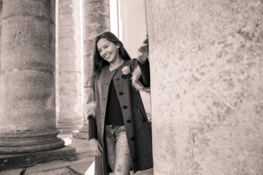 Genç, çekici, uzun saçlı güzel kız eski binanın arkasında, güneşin ilk ışıklarında duran kolye.